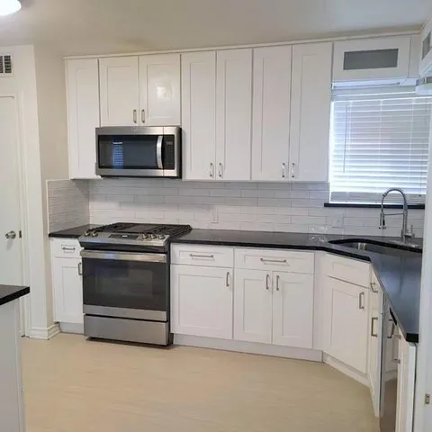 a kitchen with granite countertop white cabinets and stainless steel appliances