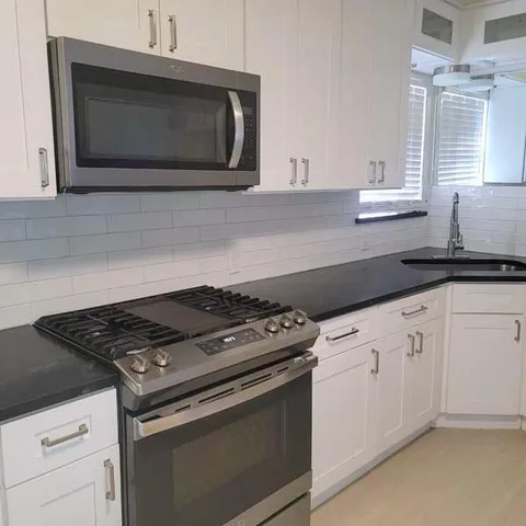 a kitchen with granite countertop white cabinets stainless steel appliances and sink