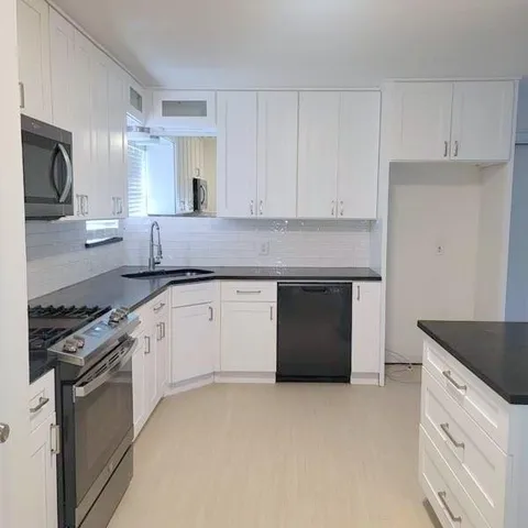 a kitchen with granite countertop white cabinets and stainless steel appliances