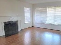an empty room with wooden floor fireplace and windows