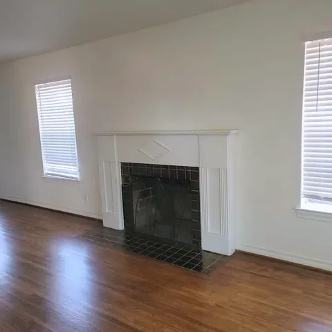 an empty room with wooden floor fireplace and windows