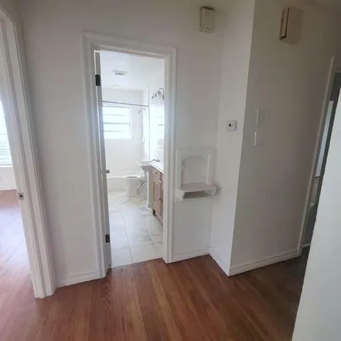 an empty room with wooden floor and a sink