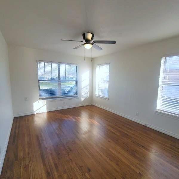 3459 Monte Carlo Street Dallas, TX 75224 - Photo 10 of 23 an empty room with wooden floor chandelier fan and windows
