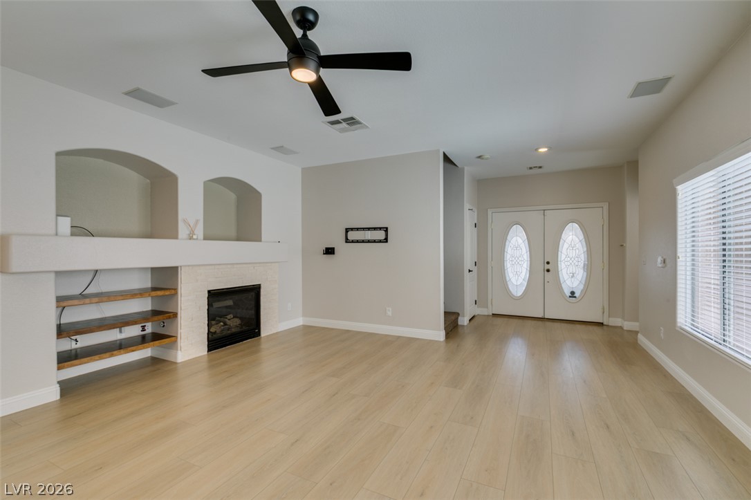 8909 Houston Ridge Avenue Las Vegas, NV 89178 - Photo 7 of 45 A spacious living area featuring light wood flooring, a modern fireplace, and elegant double entry doors.