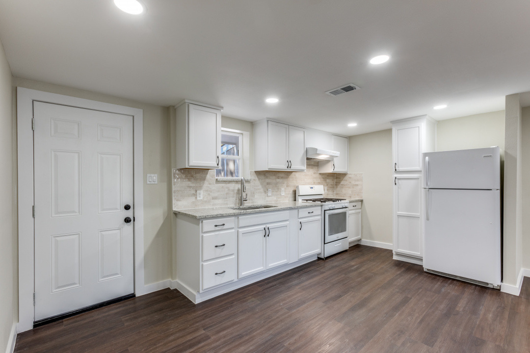 1118 Spur Street Austin, TX 78721 - Photo 12 of 27 Kitchen featuring white appliances, white cabinets, backsplash, dark wood-style floors, and recessed lighting