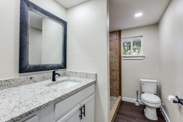 a bathroom with a granite countertop sink mirror vanity and toilet