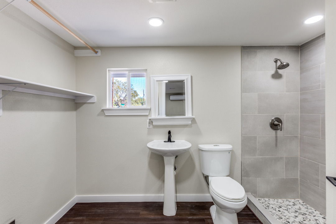 1118 Spur Street Austin, TX 78721 - Photo 20 of 27 Master bathroom with a tile shower and dark wood-style flooring