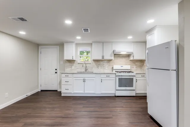 a kitchen with granite countertop white cabinets and white stainless steel appliances