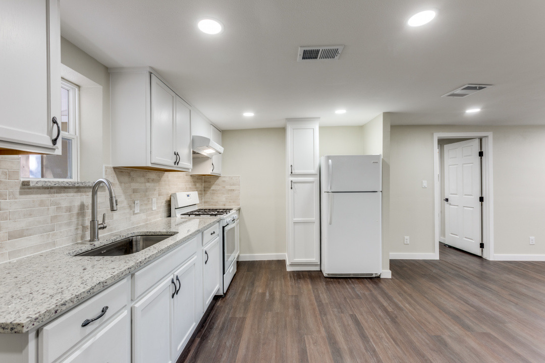 1118 Spur Street Austin, TX 78721 - Photo 5 of 27 Kitchen with white appliances, backsplash, light stone countertops, dark wood finished floors, and white cabinetry