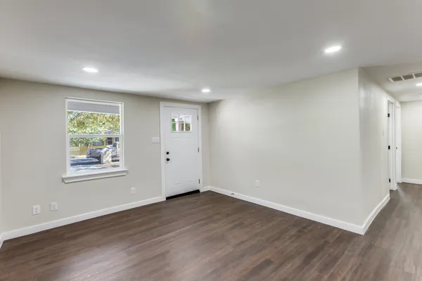 an empty room with wooden floor and windows