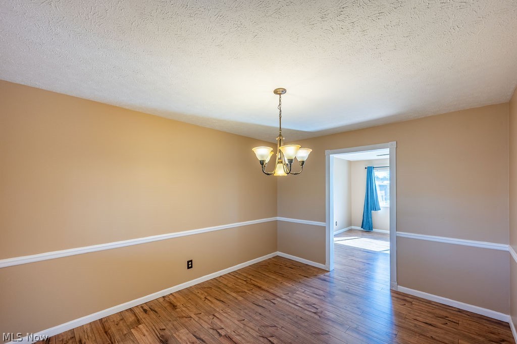 3601 River Road Vienna, WV 26105 - Photo 14 of 40 Unfurnished dining room with hanging lights, light wood-style floors, and a textured ceiling