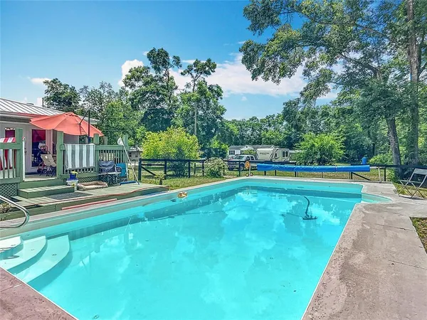 a view of a swimming pool with a bench and trees around