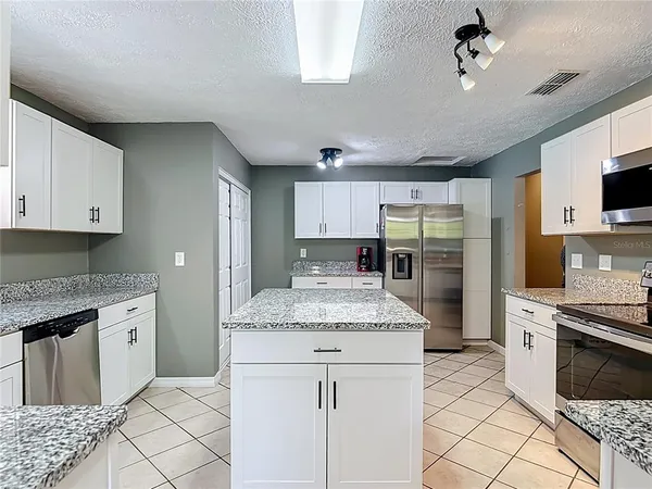 a kitchen with granite countertop a sink stainless steel appliances and cabinets