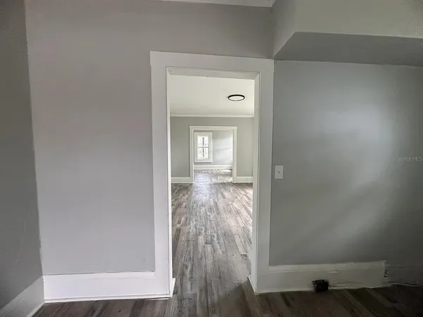 a view of a hallway with wooden floor and a livingroom
