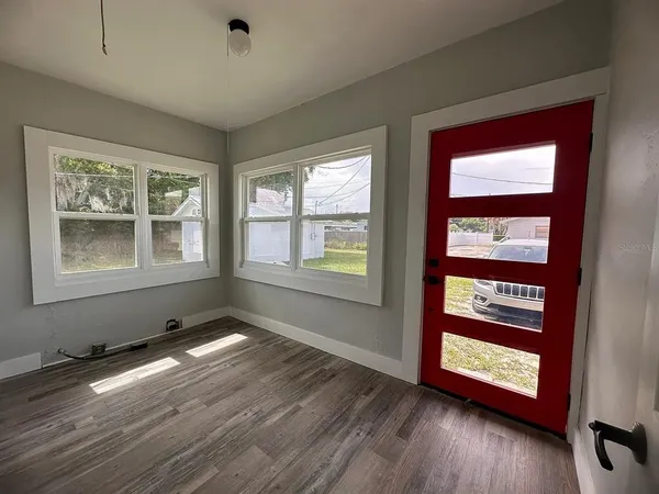 a view of an empty room with wooden floor and a window