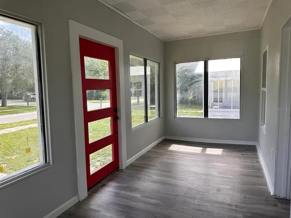a view of an empty room with wooden floor and a window