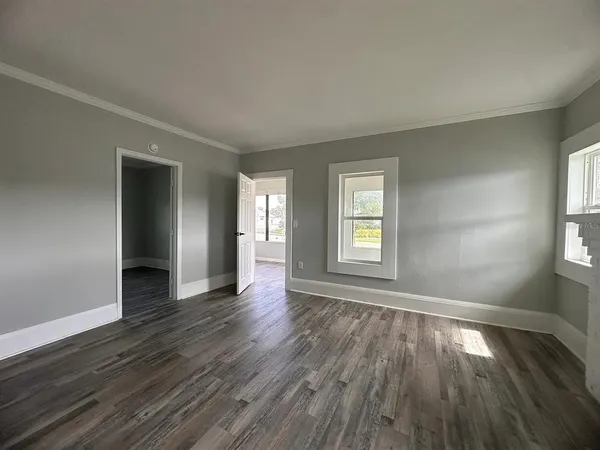 an empty room with wooden floor and windows