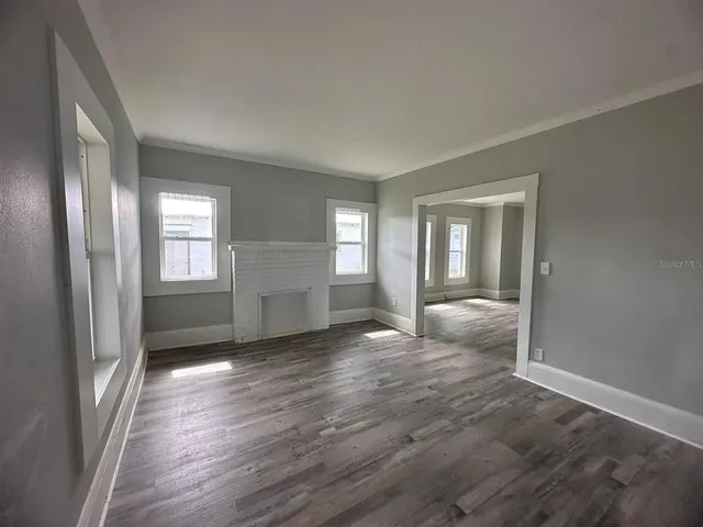 an empty room with wooden floor and windows