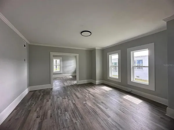 a view of an empty room with wooden floor and window