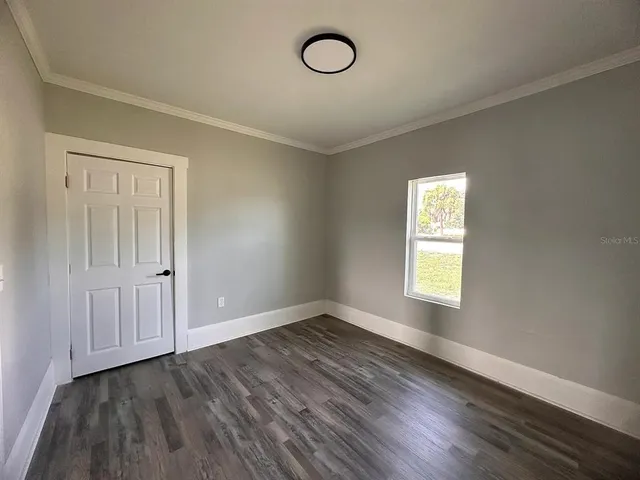 an empty room with wooden floor and window