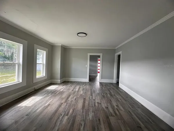 a view of an empty room with wooden floor and a window