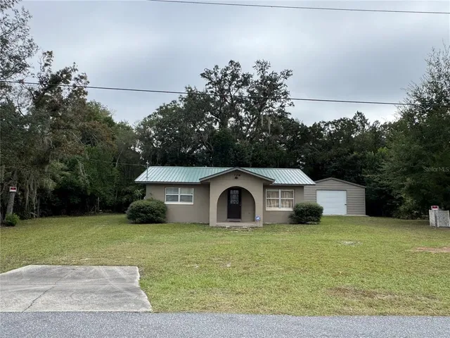 a white house with a big yard and large trees