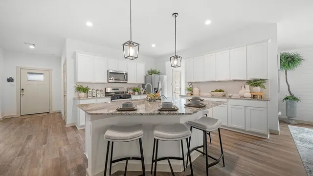 a kitchen with kitchen island a dining table chairs sink and cabinets