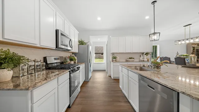 a kitchen with stainless steel appliances granite countertop a sink a stove and cabinets
