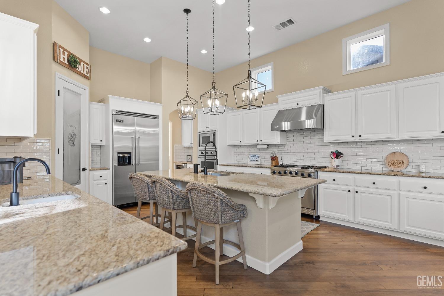 Undisclosed Address Bakersfield, CA 93314 - Photo 11 of 46 a large kitchen with cabinets a sink a stove and chairs