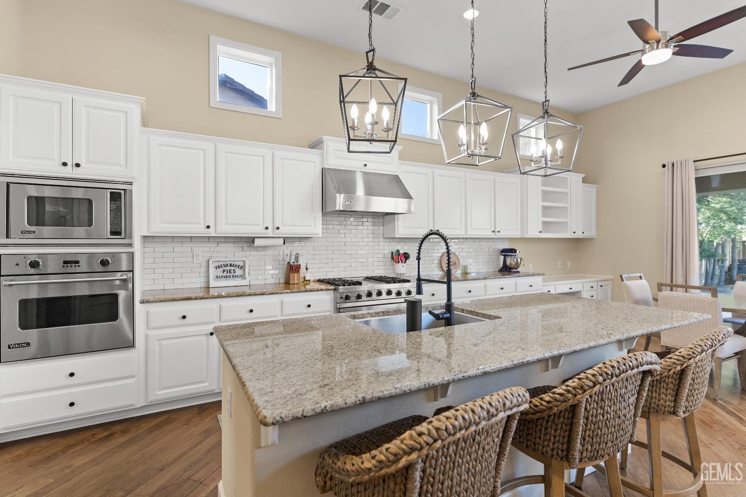 Undisclosed Address Bakersfield, CA 93314 - Photo 22 of 46 a kitchen with granite countertop a stove a sink and dishwasher with white cabinets
