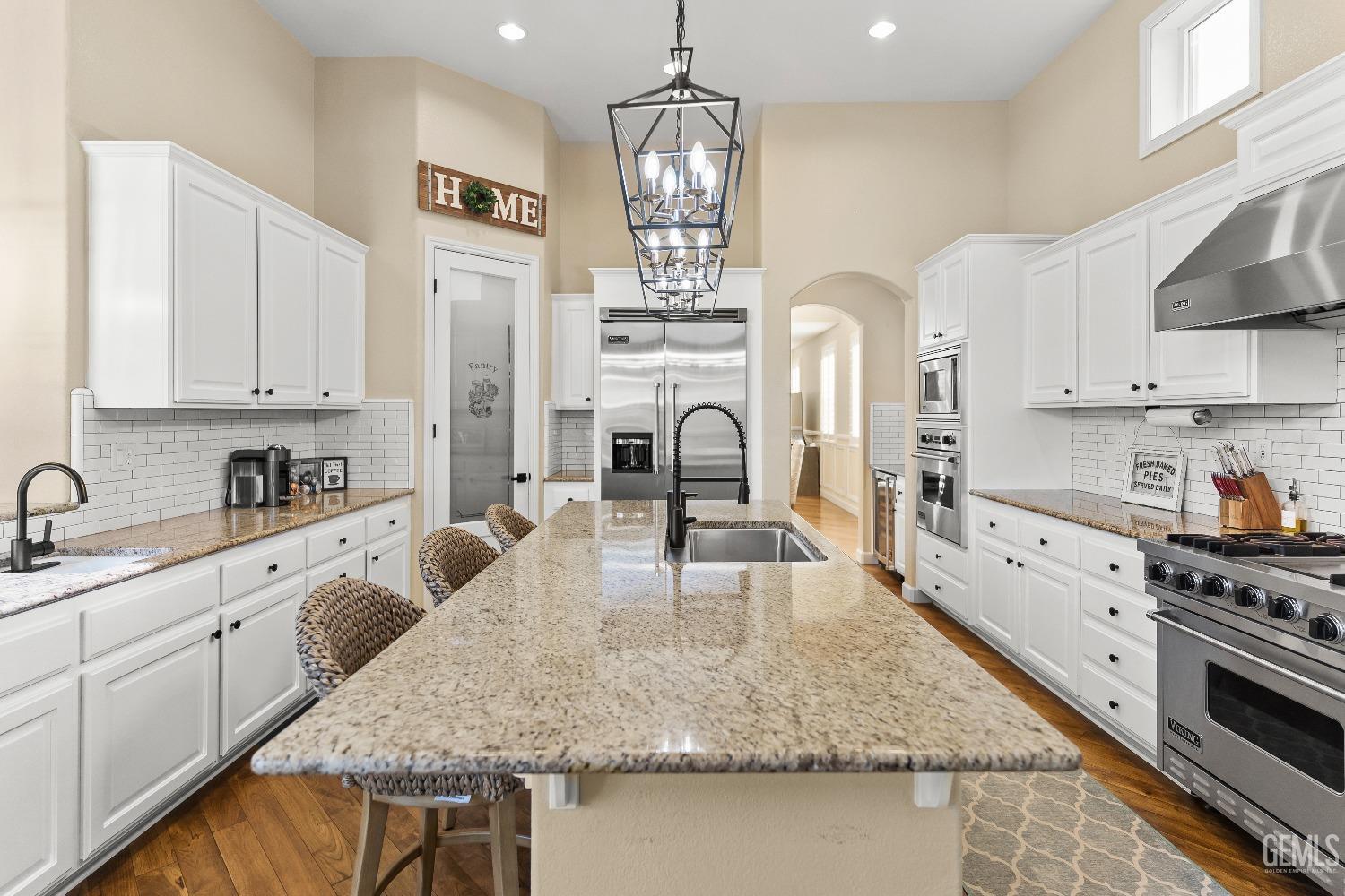 Undisclosed Address Bakersfield, CA 93314 - Photo 33 of 46 a large kitchen with granite countertop a stove a sink dishwasher and white cabinets with wooden floor