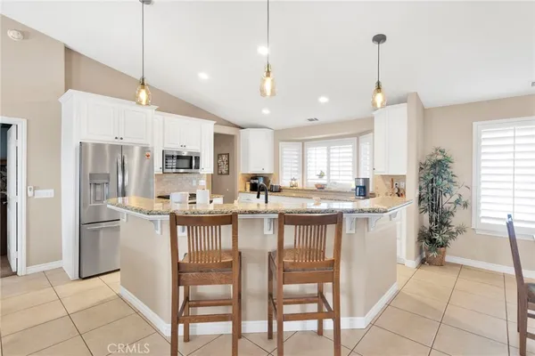 a kitchen with kitchen island granite countertop lots of counter top space and refrigerator