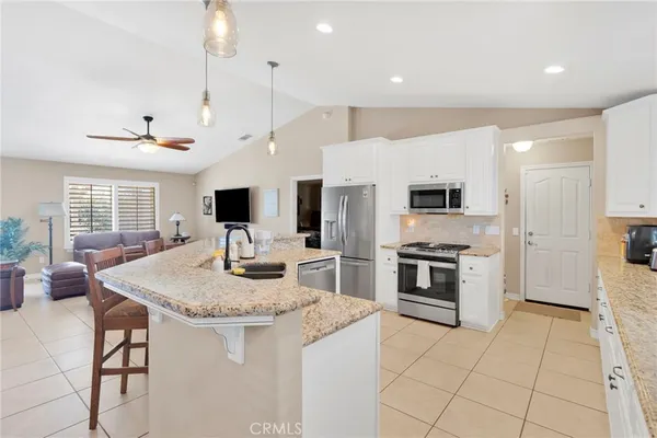 a kitchen with stainless steel appliances kitchen island granite countertop a stove a sink and a refrigerator