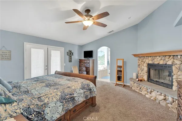 a bedroom with a large bed a flat tv screen and a fireplace with a large mirror on dresser