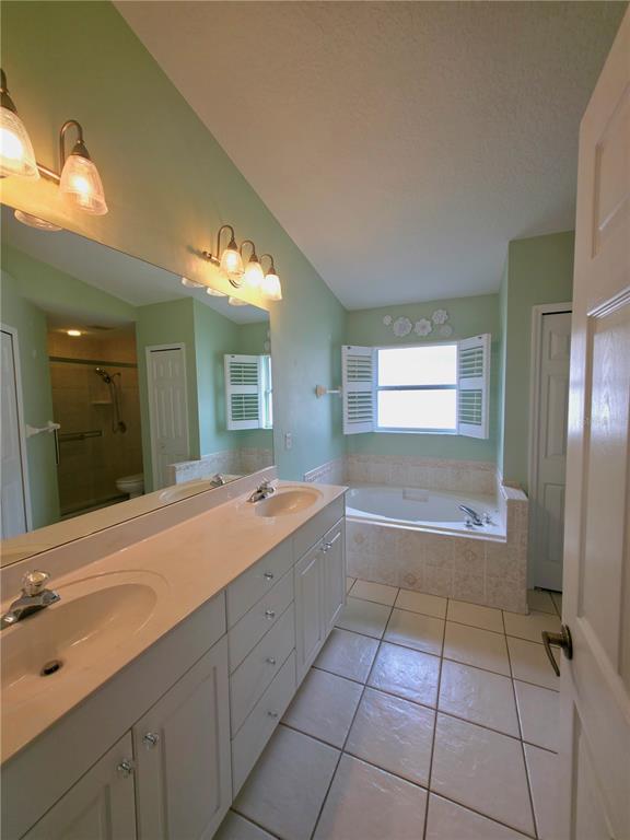 5465 High Pasture Way Melbourne, FL 32940 - Photo 17 of 39 a spacious bathroom with a granite countertop sink a toilet a mirror and shower