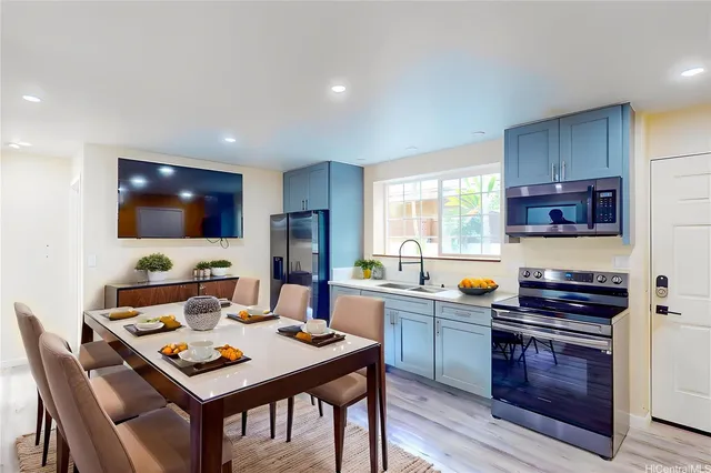 a kitchen with stainless steel appliances a kitchen island hardwood floor sink stove dining table and chairs