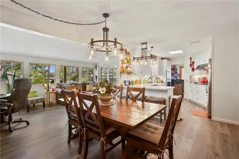 a view of a dining room and livingroom with furniture wooden floor a rug a chandelier