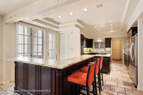 a kitchen with stainless steel appliances kitchen island granite countertop a table chairs sink and cabinets