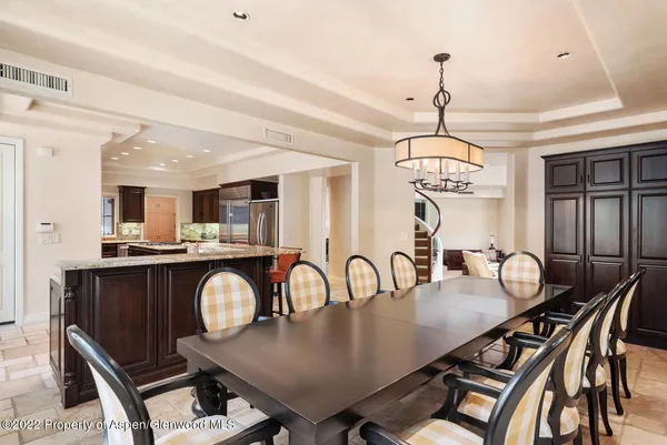 a dining room with wooden floor a chandelier a wooden table and chairs