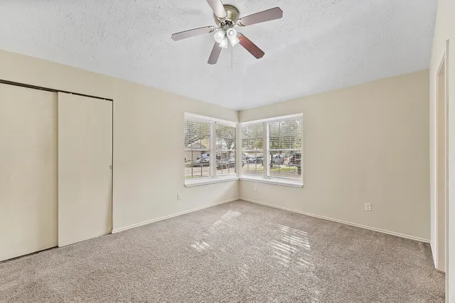 a view of an empty room with window and chandelier fan