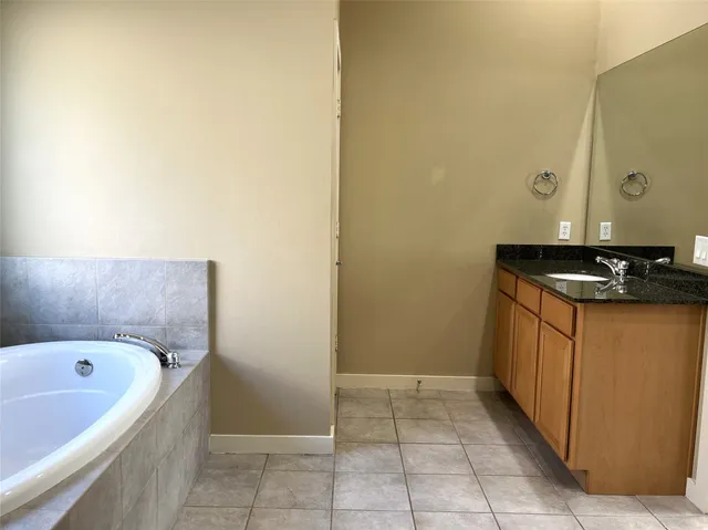 a bathroom with a granite countertop sink and a bathtub