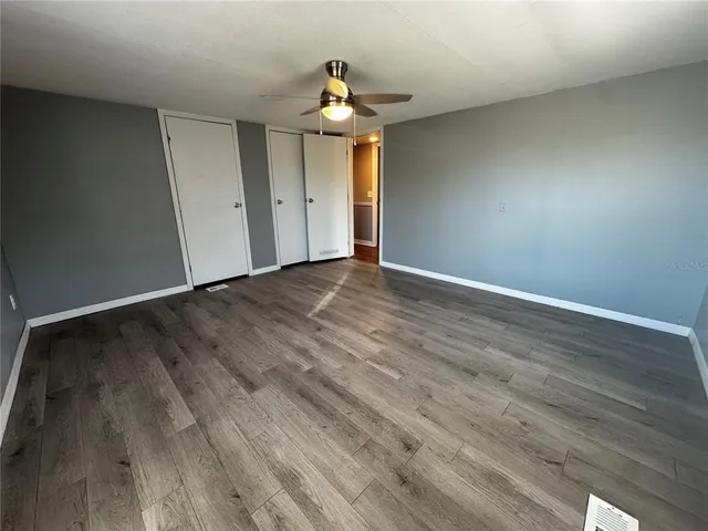 a view of empty room with wooden floor and fan