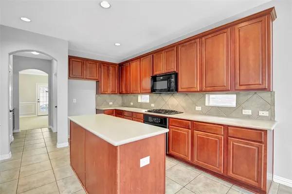 a kitchen with stainless steel appliances granite countertop a stove top oven a sink dishwasher and a refrigerator with wooden cabinets