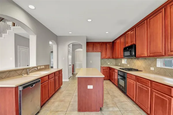 a large kitchen with stainless steel appliances granite countertop a sink counter space cabinets and a large window