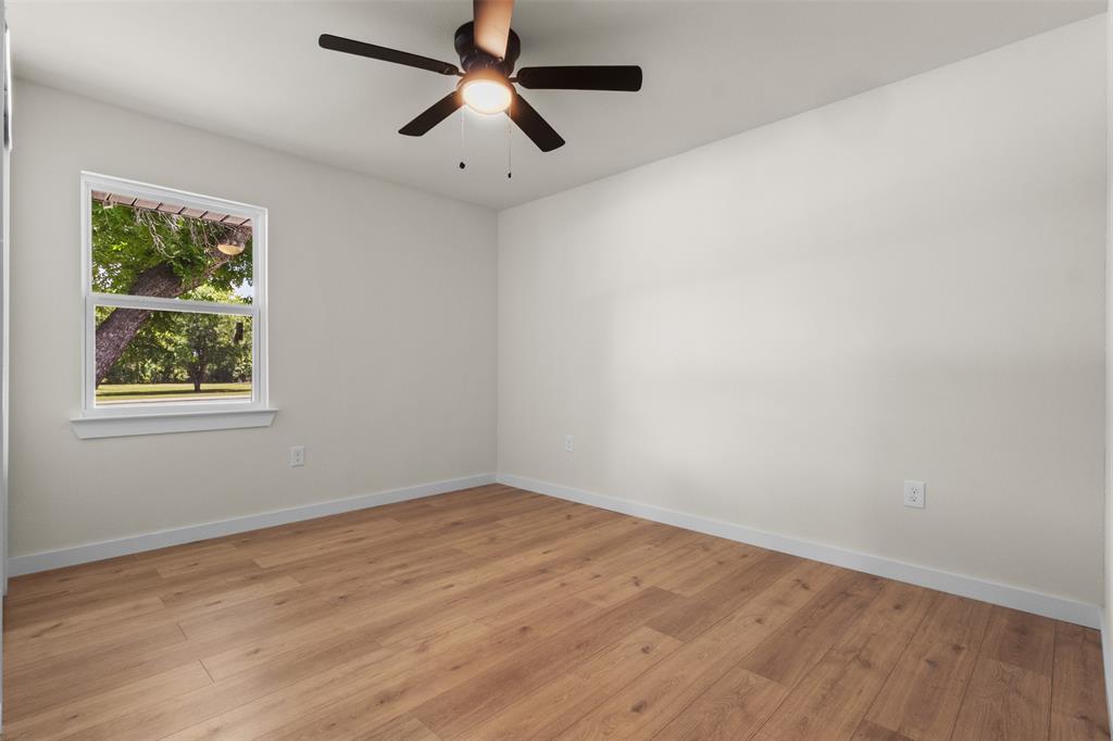 907 Pinson Road Forney, TX 75126 - Photo 20 of 35 Spacious room featuring wood-finish flooring, light-toned walls, and a ceiling fan with integrated lighting
