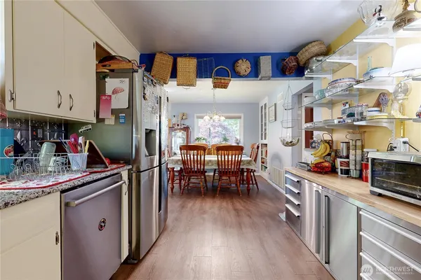 a kitchen with stainless steel appliances a refrigerator a stove a dining table and chairs