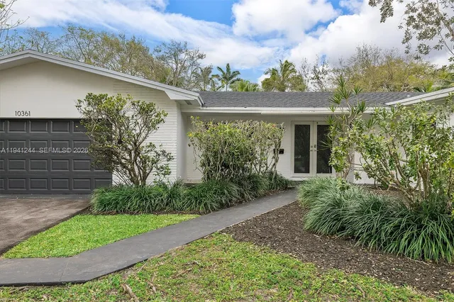 a view of a yard in front of a house with a large tree
