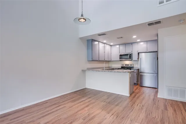a kitchen with a refrigerator and white cabinets with wooden floor