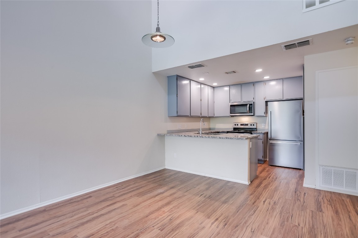 1748 Ohlen Road, Unit 36 Austin, TX 78757 - Photo 7 of 21 a kitchen with a refrigerator and white cabinets with wooden floor