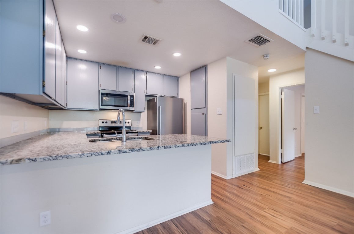 1748 Ohlen Road, Unit 36 Austin, TX 78757 - Photo 8 of 21 a kitchen with stainless steel appliances granite countertop wooden cabinets a refrigerator a sink a stove a microwave and wooden floors